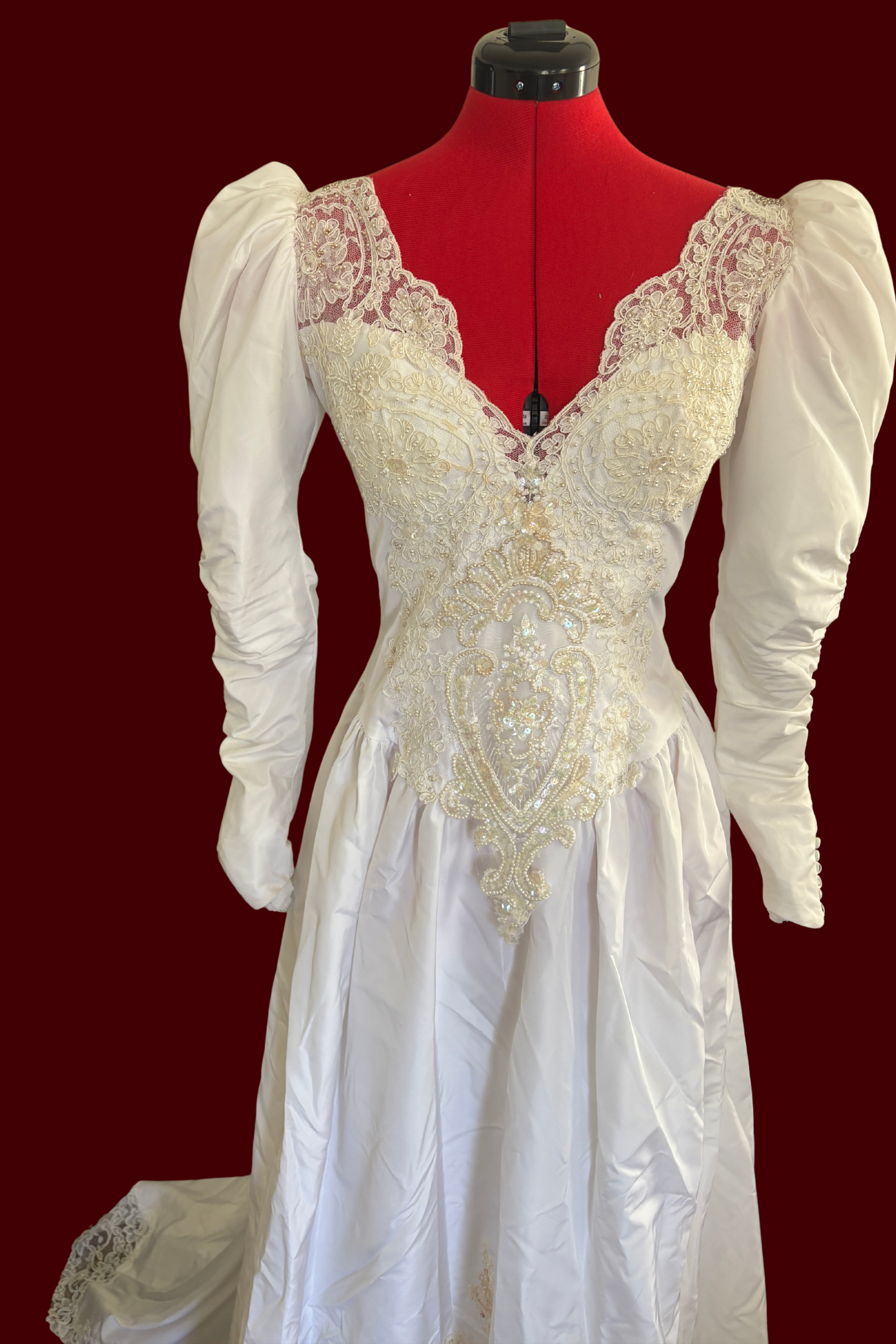White lace dress on a red mannequin against a dark red background